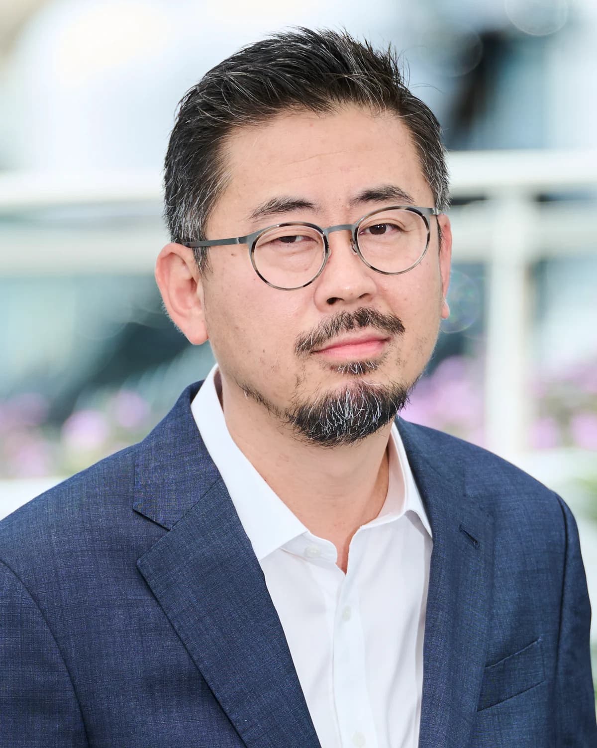 Director Na Hong-jin wearing glasses and a blue jacket at the HOPE photocall in Cannes on May 18, 2026