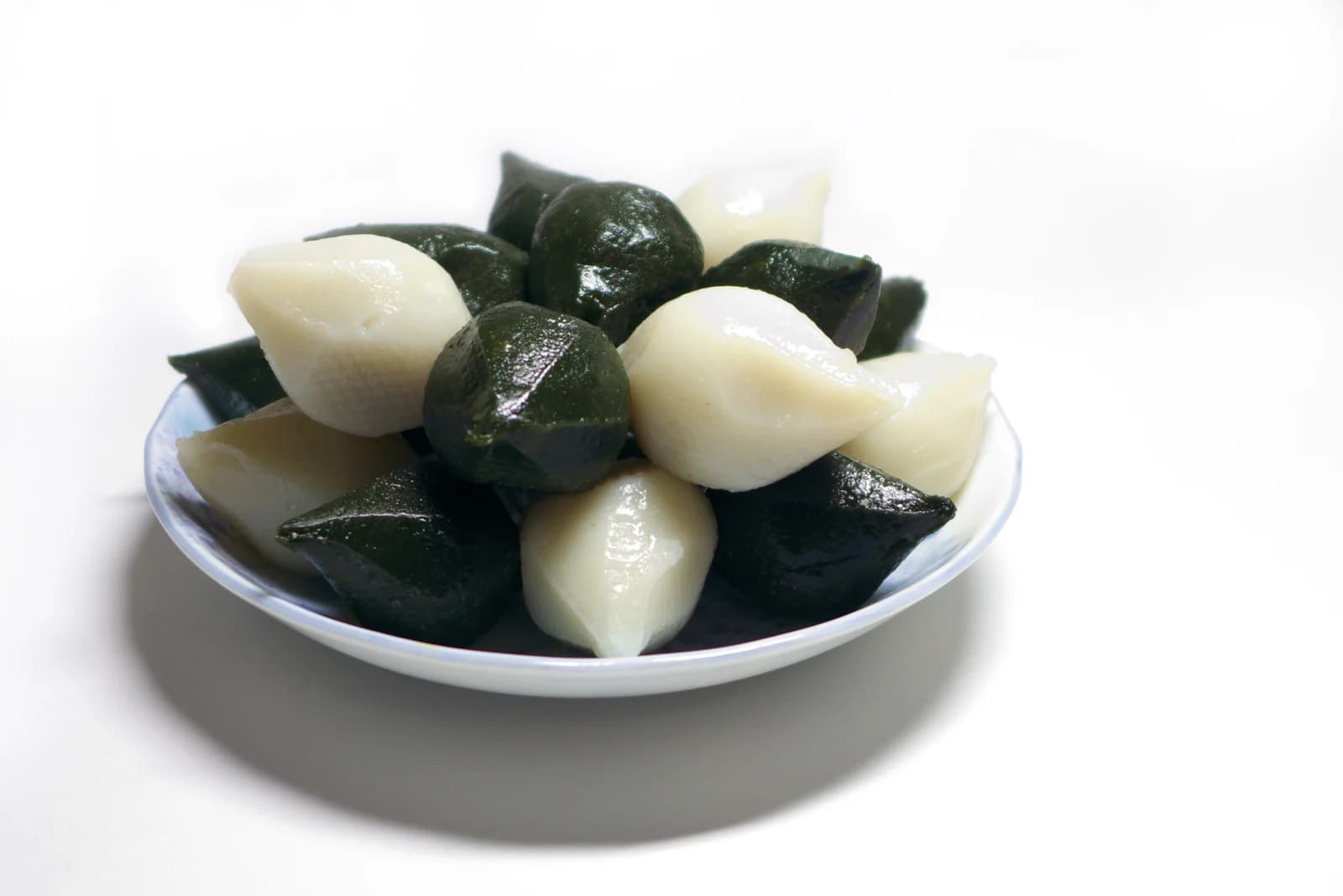 White and green crescent-shaped songpyeon rice cakes on a plate.
