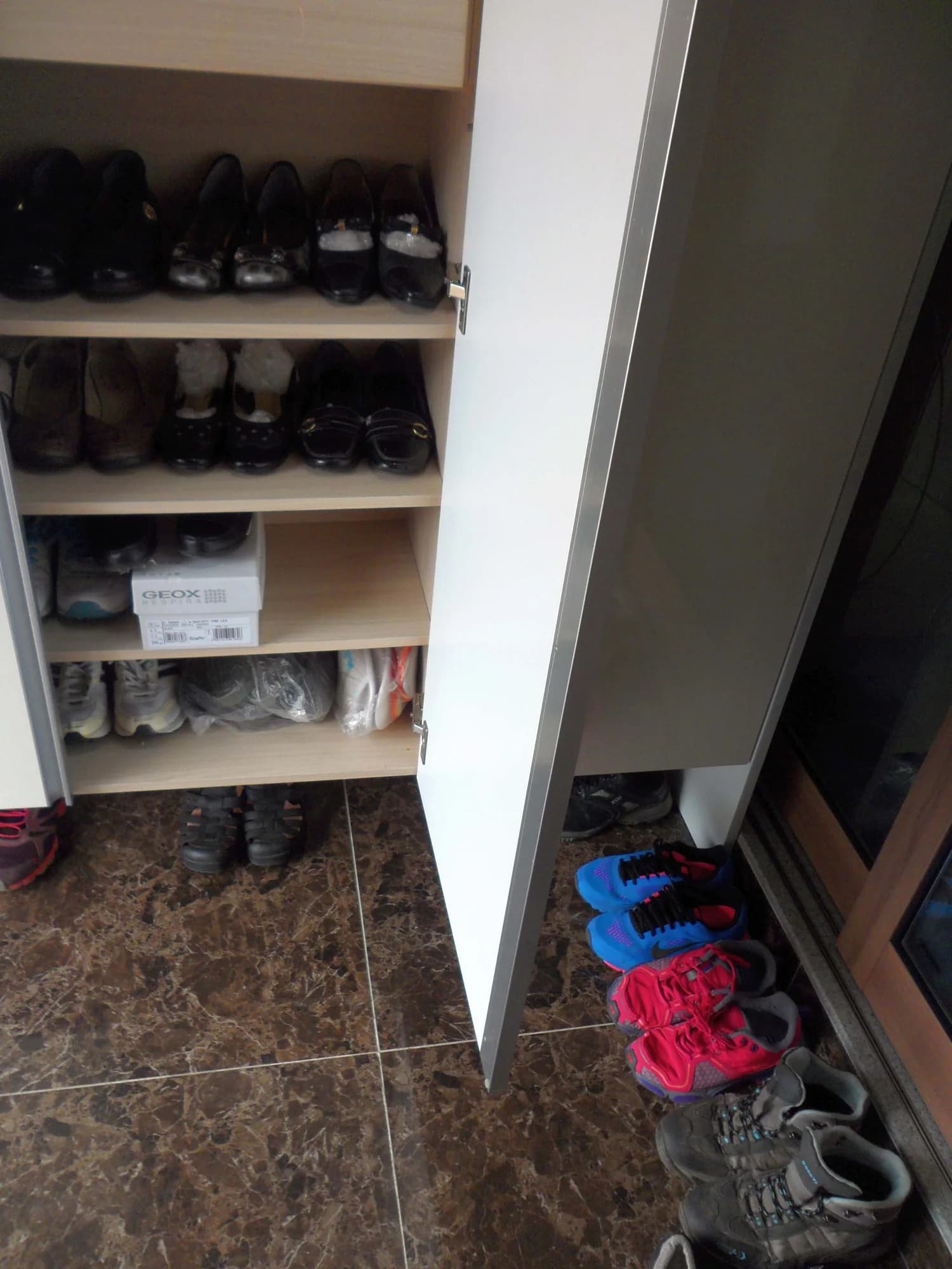 An open shoe cabinet beside the tiled entrance floor of a Korean home
