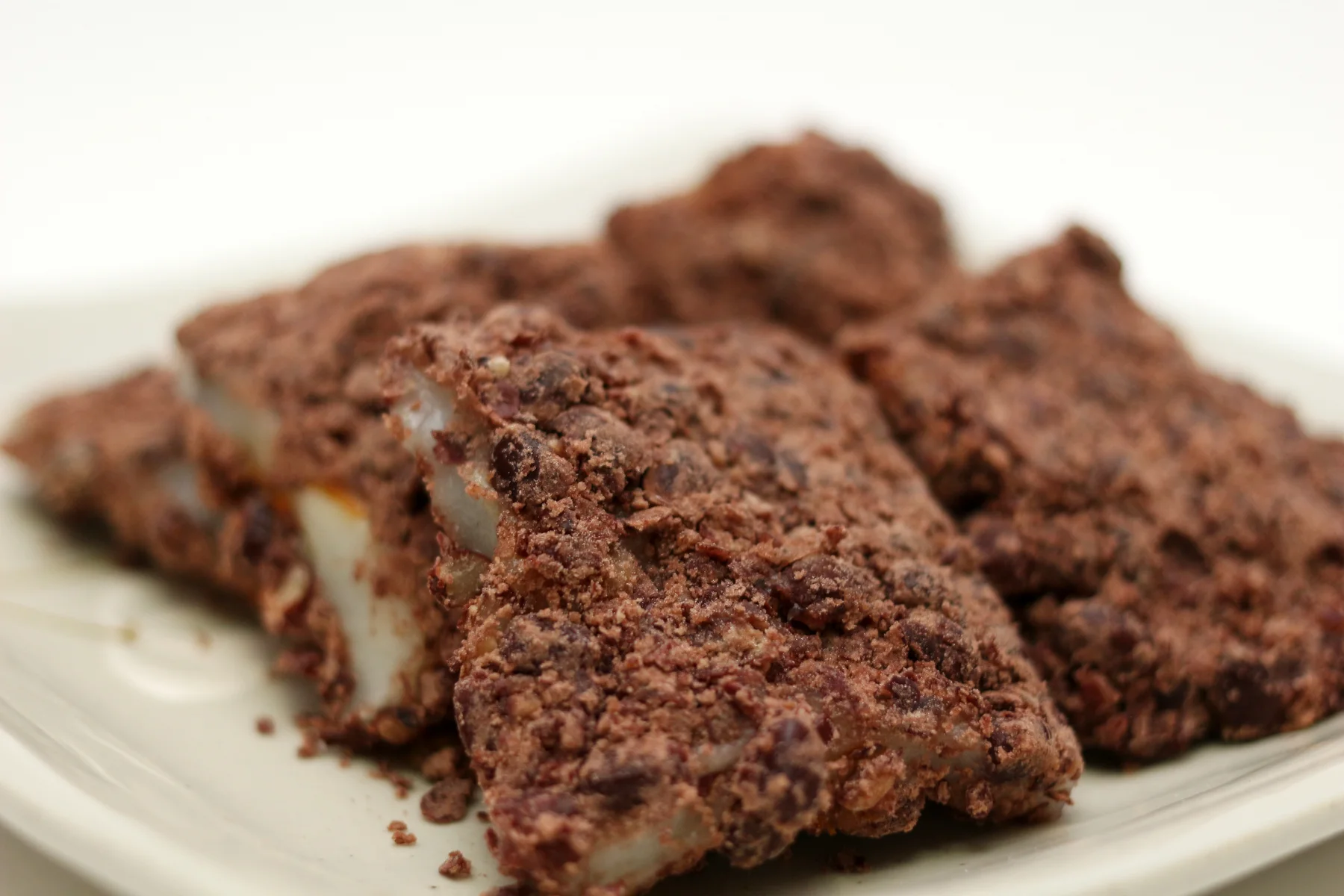 Slices of brown, crumbly-topped steamed rice cake on a white plate.
